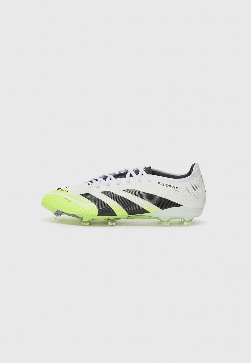 Botas de fútbol blancas y negras con acentos en verde, parte superior texturizada, seis tacos transparentes y diseño de malla. Presenta un destacado logotipo en el lateral.