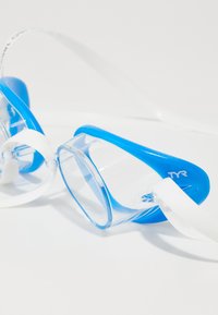 Occhialini da nuoto TYR con lenti trasparenti, montatura in silicone blu, cinghia regolabile bianca e design aerodinamico per una vestibilità sicura.