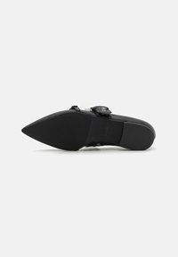 Pantofii negri cu vârf ascuțit au un superior din piele netedă, detalii decorative cu cataramă și o talpă din cauciuc texturat pentru aderență.