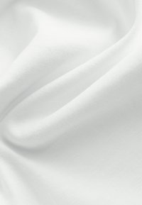 Tela de algodón blanca con una textura suave, patrón de tejido fino visible y caída lisa, que muestra sutiles arrugas y pliegues.