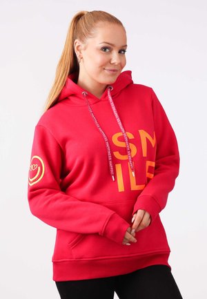 Felpa rossa con la scritta "SMILE" stampata in arancione, dotata di tasca frontale e lacci regolabili. Accentuata con un logo a faccina sorridente sul maniche.