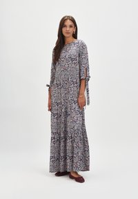 Maxi sukienka w ciemnonawowym kolorze z paisley w kolorze czerwonym i białym; posiada rękawy trzy czwarte z wiązaniami oraz luźny fason.