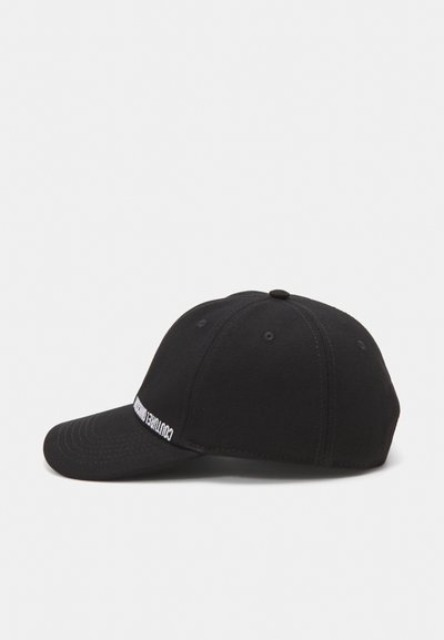 Casquette de baseball noire avec une visière courbée, fabriquée à partir d'un tissu texturé. Présente des coutures décoratives et un logo blanc sur le devant.