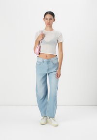 Valge läbipaistev lühike topp, helesinised laiad teksad ja valged tossud. Kaasas väike roosa kott. Keskenduge minimalistlikule disainile ja igapäevasele stiilile.