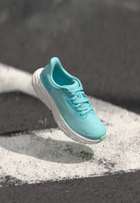 Light blue running shoe with textured mesh upper, cushioned sole, and white accents. Features a rounded shape and lacing system.