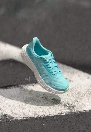Baskets de course bleu clair avec un dessus en maille texturée, semelle rembourrée et accents blancs. Présente une forme arrondie et un système de laçage.