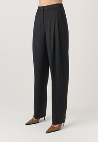 Fekete szabott nadrág magas derékkal, elején redőzéssel és egy gombos zárással. Az anyag simának tűnik, jól definiált sziluettel.