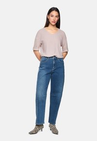Helles pinkes Kurzarmoberteil, lockere Passform, kombiniert mit hoch taillierten blauen Denim-Jeans und Leopardenmuster-Stilettos. Einfaches Design mit subtilen Details.