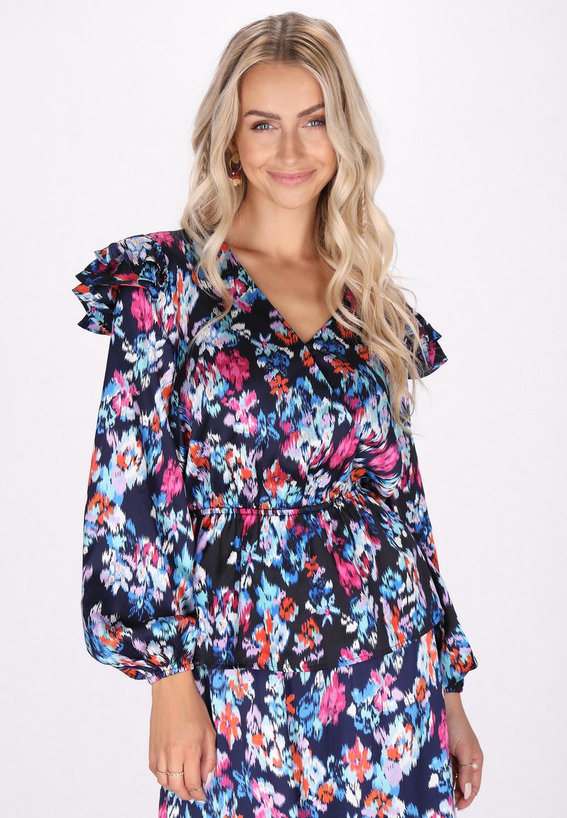 Květinová blůza s námořnickým pozadím a živými růžovými, modrými a oranžovými vzory. Dlouhé rukávy s volánkovými akcenty a výstřihem do V.