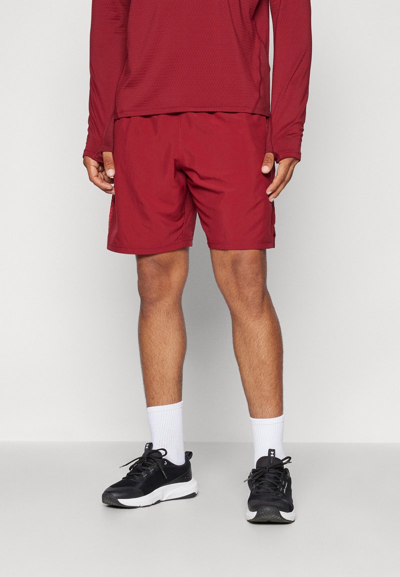 Pantalones cortos deportivos color burdeos con un acabado texturizado, combinados con una camiseta de manga larga a juego. Llevado con zapatillas negras y calcetines blancos hasta el tobillo.