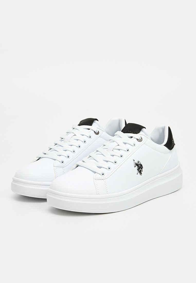 Baskets synthétiques blanches avec une texture lisse, un tirant noir au talon, un bout rond, un design à lacets et un petit emblème noir sur le côté.
