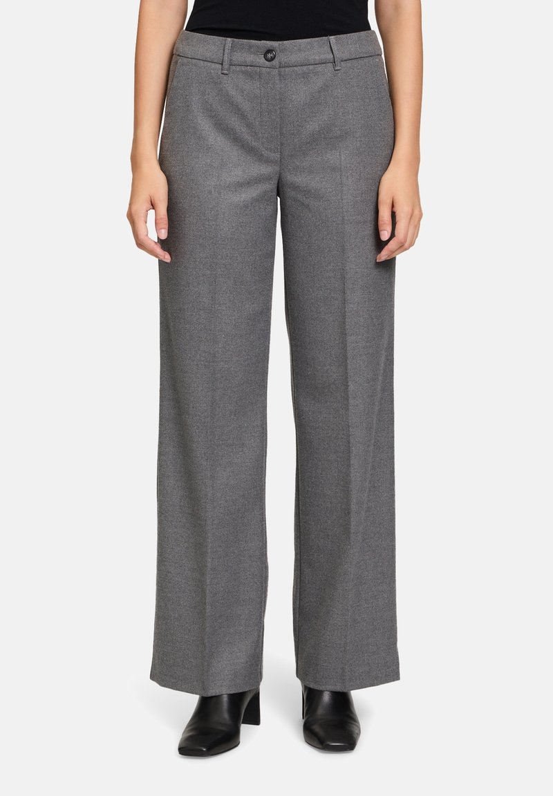 Pantalon large gris en tissu texturé, doté d'une fermeture à bouton sur le devant et de poches latérales, associé à des bottes à talons noires.