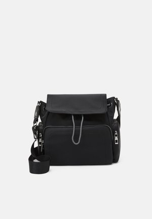 Zwarte schoudertas met voorkant ritspocket, klep sluiting, verstelbare riem en zijvakken met rits op een witte achtergrond.