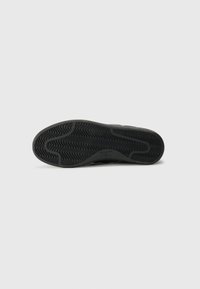 Suola di sneaker nera in gomma con un motivo a onde, bordi lisci e un'impronta di logo discreta. Testurizzata per una presa sicura e una maggiore durabilità.
