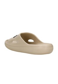 Scarpa beige senza lacci con retro aperto, caratterizzata da ritagli circolari e suola con texture scanalata. Realizzata in materiale flessibile con dettagli minimi.