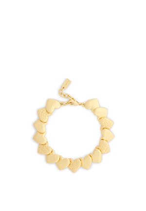 Bracelet en or avec des maillons en forme de cœur alternant lisses et texturés, et un fermoir réglable avec une petite étiquette rectangulaire.