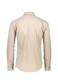 Camicia beige a maniche lunghe realizzata in tessuto morbido, con colletto classico, polsini con bottoni e orlo curvo. Le cuciture visibili ne esaltano la struttura.