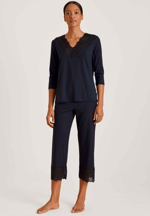 Navy two-piece loungewear set made of soft fabric, featuring a V-neck top with lace trim and cropped pants with lace accents at the hem.
