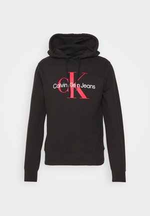 Felpa nera con cappuccio e lacci sul davanti, con grande logo rosso "cK" e "Calvin Klein Jeans" bianco centrato sul petto.