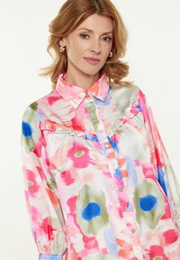 Bluse mit floralem Muster in Rosa-, Blau- und Grüntönen. Verfügt über einen Kragen, eine geraffte Vorderseite und eine Knopfverschluss. Seidige Textur.
