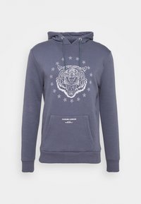 Felpa in cotone blu navy con grafica di una tigre circondata da stelle, tasca frontale a marsupio e cappuccio regolabile con cordino. Tessuto morbido con polsini a coste.