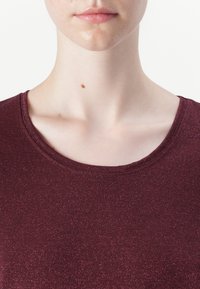 Burgundy kortärmad skjorta med rund halsringning, tillverkad av ett strukturerat, glittrande tyg som har subtila inslag av lyster genom hela plagget.