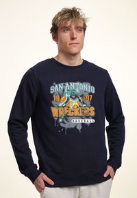 Mörkblå sweatshirt med rund halsringning, med ett grafiskt tryck av en robot och texten "San Antonio Wreckers Baseball" i orange och teal.