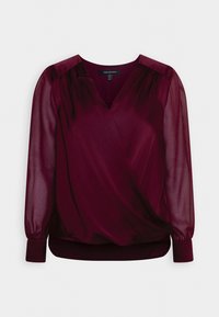 Blusa avvolgente bordeaux con maniche trasparenti, scollatura a V, orlo elasticizzato e dettagli arricciati sulle spalle. Tessuto morbido, silhouette elegante.
