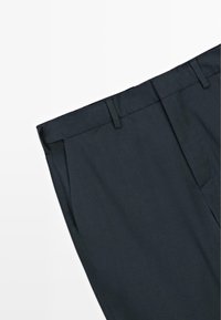 Pantaloni grigi scuri con una texture del tessuto liscia, caratterizzati da una fronte piatta, piega netta e passanti per cintura. Nessun motivo visibile o decorazioni.
