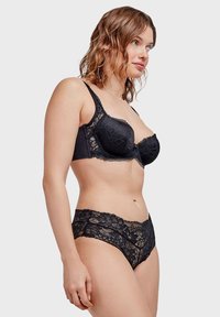 Soutien-gorge en dentelle noire avec armature et motif floral, associé à une culotte en dentelle noire assortie avec une taille festonnée.