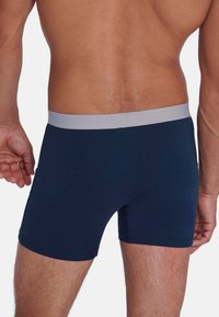 Boxer briefs blu navy realizzati in tessuto morbido, con un elastico grigio chiaro in vita. Il design include una forma classica aderente.