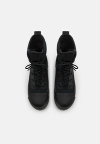 Schwarze wasserdichte Stiefel mit Schnürung an der Vorderseite, gepolstertem Kragen und gummierter Zehenkappe. Knoten-Detail oben für einen sicheren Sitz. Insgesamt glatte Textur.