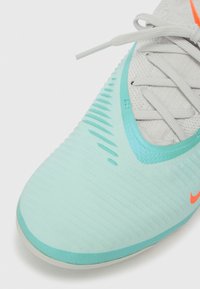 Gaiši zili tenisu ar teksturētu augšdaļu, oranžiem akcentiem un izsmalcinātu formu. Iezīmēts ar auklu aizdari un kontūrveida zoli.