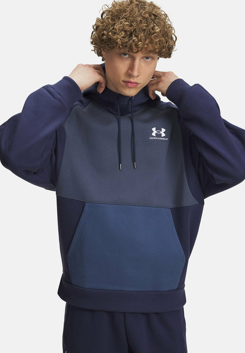 Marineblaue Kapuzenjacke mit einem zweifarbigen Design, das ein hellgraues Vorderteil, eine Kordelzugkapuze und eine Vorderasche aufweist. Under Armour-Logo sichtbar.