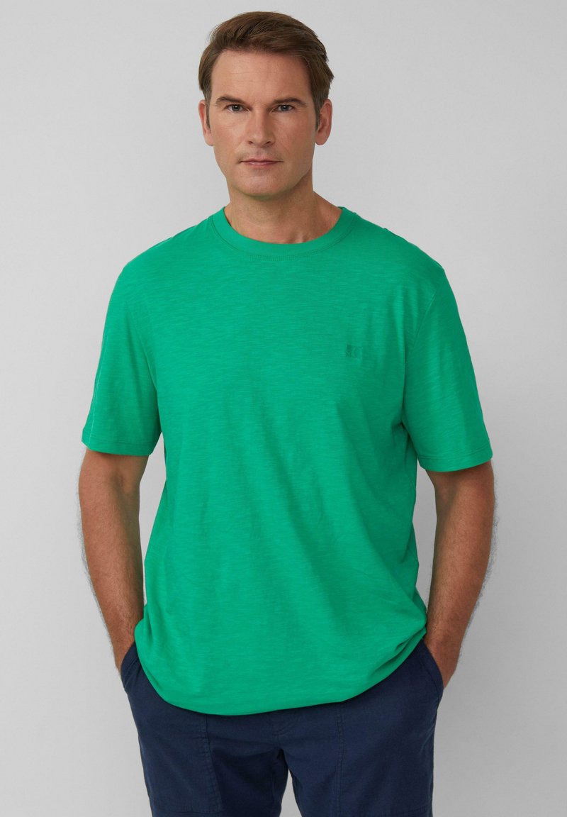 Zielony t-shirt z okrągłym dekoltem, wykonany z lekkiej, teksturowanej tkaniny. Krótkie rękawy w luźnym kroju, z dyskretnym logo na piersi.