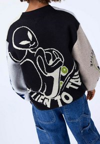 Stickad tröja med ett grafiskt utomjordiskt motiv i svart och kräm, med blå och grå ton accenter. Avslappnad passform, ribbad halsringning och strukturerat mönster.