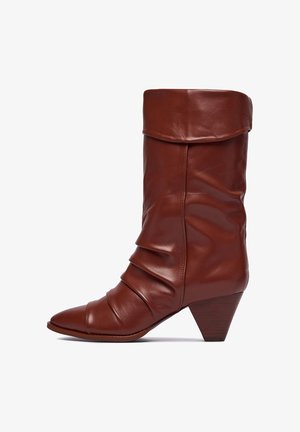 Hnedá kožená členková čižma s voľným dizajnom, špicatou špičkou a stohovaným kužeľovitým podpätkom. Má plisované detaily na holeni.