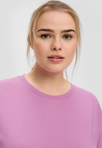 Lichtpaarse T-shirt met korte mouwen en een ronde halslijn, gemaakt van een zachte, gladde stof. Eenvoudig ontwerp, zonder zichtbare patronen of accenten.
