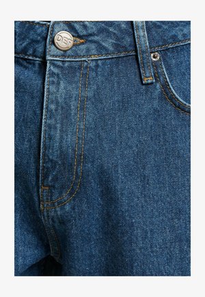 Jean en denim bleu avec une fermeture éclair, un bouton avec gravure "DEF" et des coutures oranges contrastantes sur les poches et les coutures.