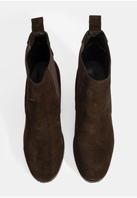 Bruine suède enkellaarzen met een gladde textuur, voorzien van elastische zijkanten en een trekband voor eenvoudig aan- en uittrekken. Rond afgewerkte neus.