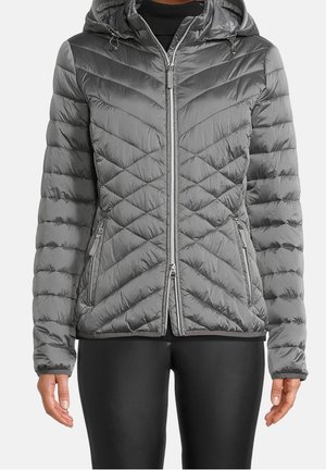 Szara pikowana kurtka z kapturem, zapinana na zamek z przodu oraz z kieszeniami na zamek, noszona z czarnymi dopasowanymi spodniami.