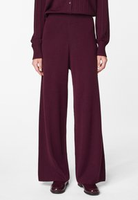 Pantalons à jambe large d'une couleur bordeaux profonde, fabriqués à partir d'un matériau tricoté doux. Présentent une taille haute et une texture lisse.