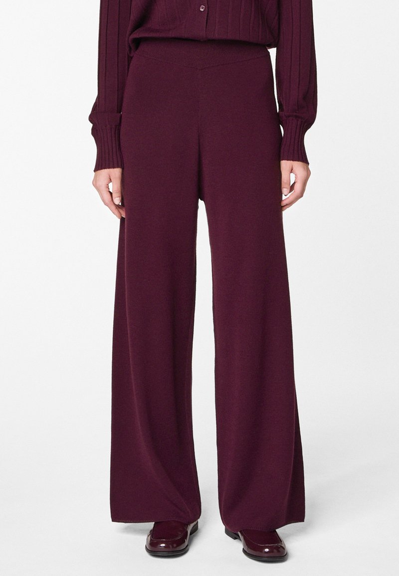 Pantalons à jambe large d'une couleur bordeaux profonde, fabriqués à partir d'un matériau tricoté doux. Présentent une taille haute et une texture lisse.