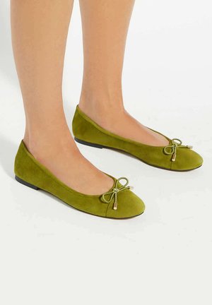 Green suede ballet flats with a rounded toe, featuring a small bow and gold-tone accents at the front. Low, black rubber sole.