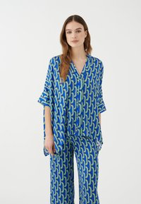 Conjunto de pijama azul y verde con un patr�ón que incluye una blusa de corte holgado, con escote en V y mangas amplias, acompañada de pantalones a juego.