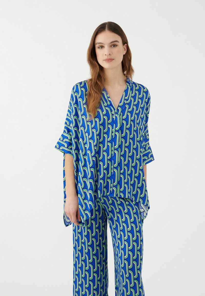 Conjunto de pijama azul y verde con un patrón que incluye una blusa de corte holgado, con escote en V y mangas amplias, acompañada de pantalones a juego.