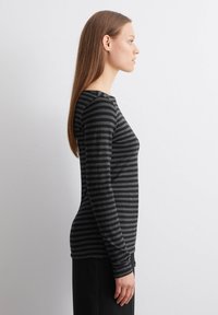 Svart og grå stripete langermet skjorte med rund hals og tettsittende silhuett, laget av et mykt stoff. Ingen distinkte mønstre eller aksenter.