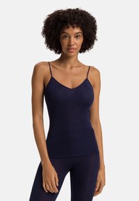 Námořnický modrý, přiléhavý top na ramínka s tenkými popruhy a výstřihem do V, vyrobený z jemného materiálu. Povrch vypadá hladce a pružně.