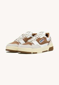 Sneaker bianchi e marroni realizzati in materiale scamosciato e in pelle, con suola testurizzata, design con lacci e un logo visibile sul lato.