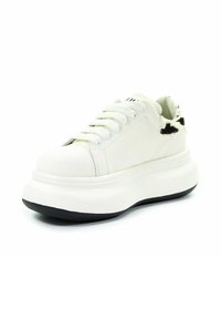 Biała platforma sportowa z grubą czarną podeszwą, białymi sznurówkami i czarno-białym futerkiem na kołnierzu pięty, skierowana w lewo.